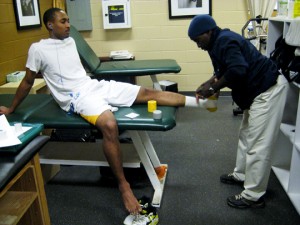 Therapist Molon Bromfield tapes up b-ball player Kern Lewis. Photo by Jason Novick