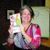 PHOTO BY MELINDA WARREN // Kathleen Burke, program manager for the Shazaam program holding up one of the graphic novels from one of the grade seven classes from the June 2011 edition.